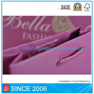 매듭이 달린 손잡이가 달린 자주색 종이 봉투